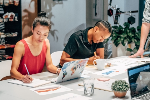 Colleagues sitting at a table writing in notebooks