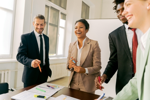 Colleagues standing around a table working and smiling