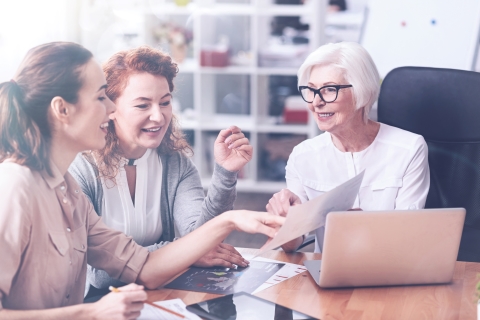 Three coworkers from different generations looking and pointing at a paper